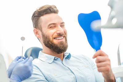 man with white teeth smiling at the mirror